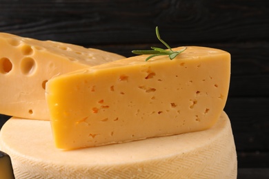 Photo of Different types of delicious cheese against black background, closeup