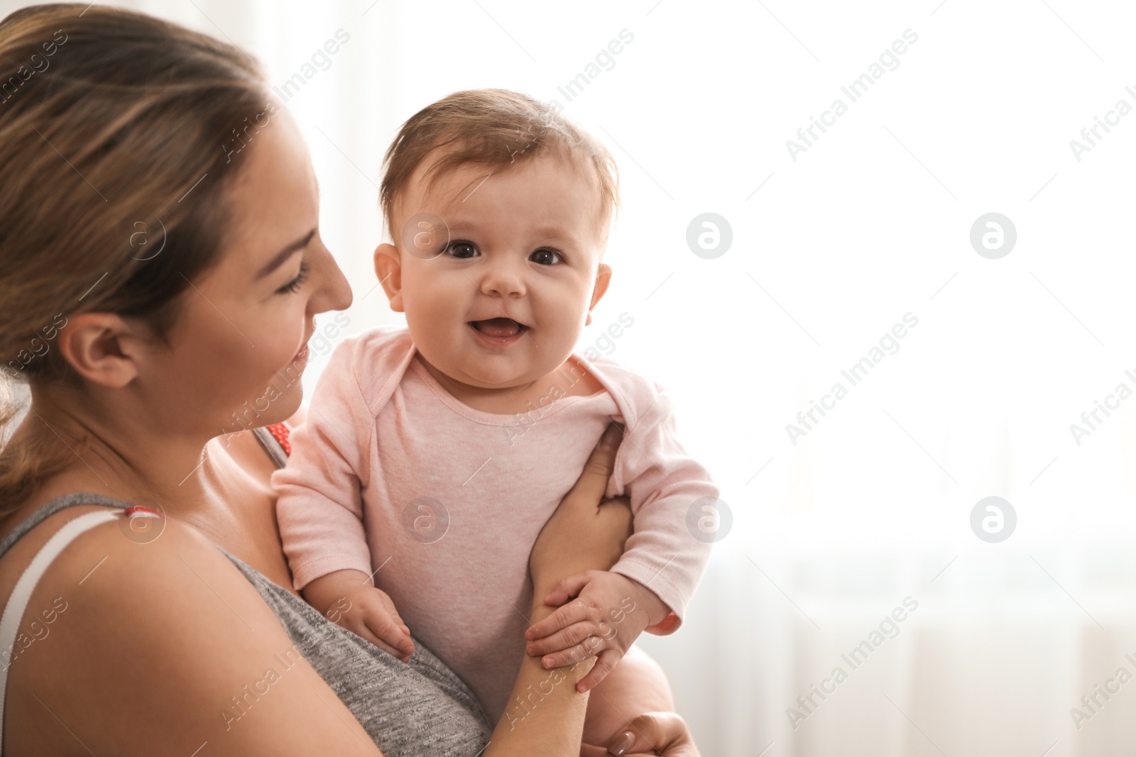 Photo of Young woman with her cute baby at home. Space for text