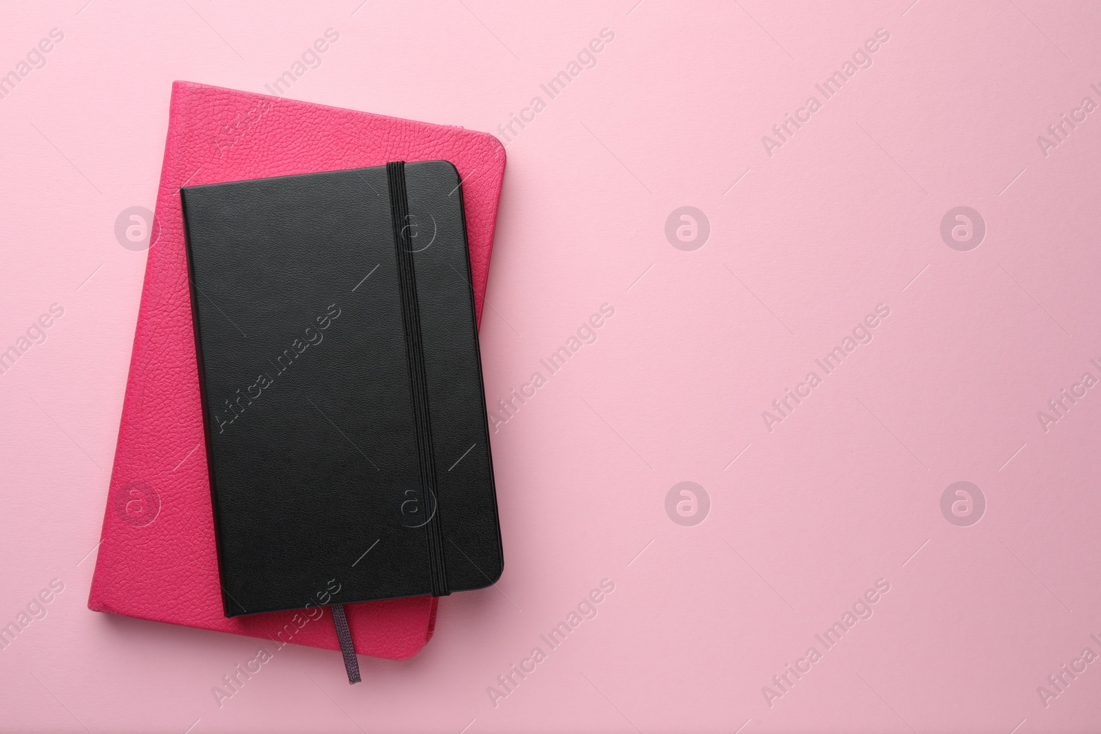 Photo of Different notebooks on light pink background, top view. Space for text