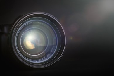 Image of Modern camera lens on black background, closeup. Space for text