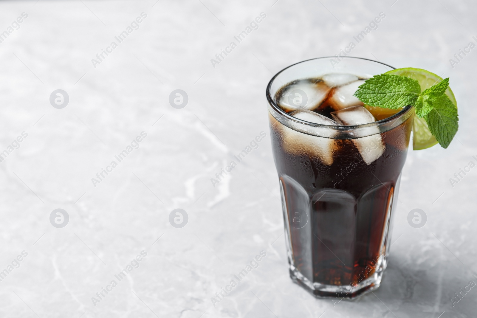 Photo of Glass of tasty refreshing cocktail on marble table. Space for text