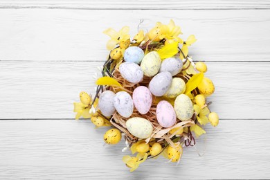 Photo of Festively decorated Easter eggs on white wooden table, top view