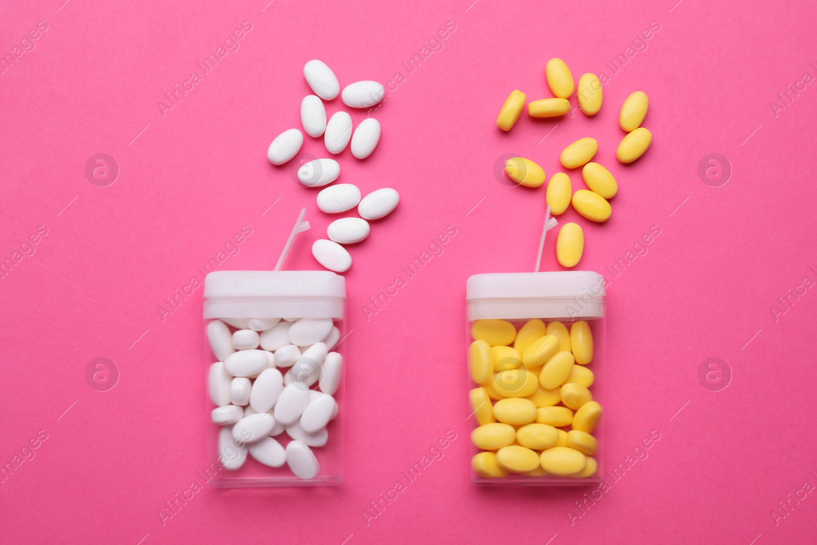 Photo of Containers and different dragee candies on pink background, flat lay