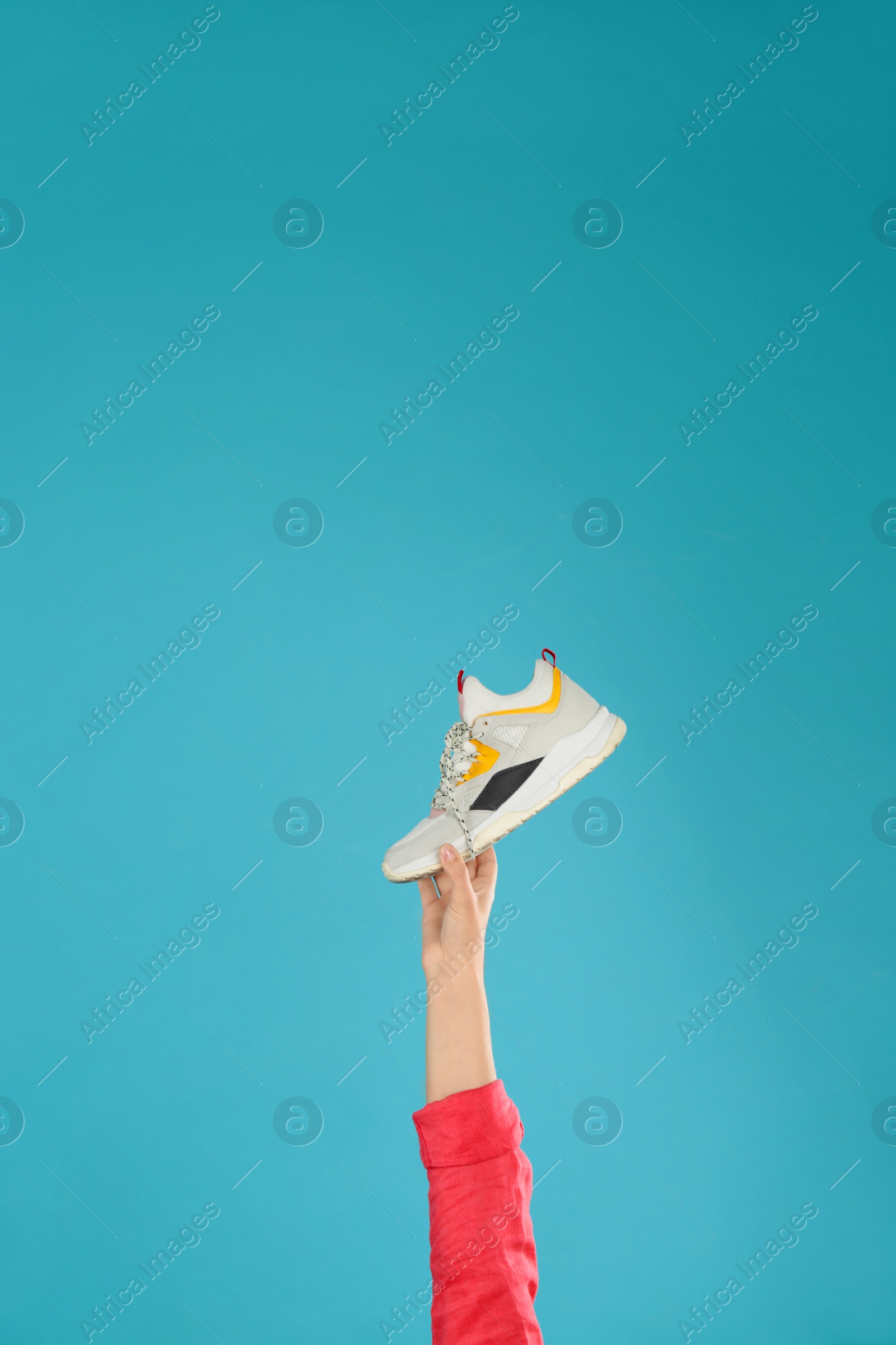 Photo of Young woman holding comfortable shoe on light blue background, closeup. Space for text