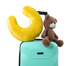 Soft travel pillow and toy bear on turquoise suitcase isolated on white