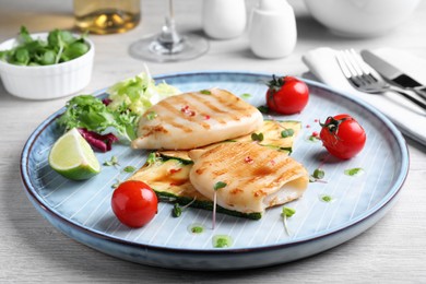 Photo of Grilled squid tubes with vegetables served on white wooden table