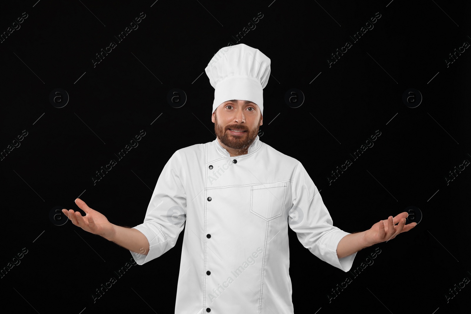 Photo of Puzzled mature male chef on black background