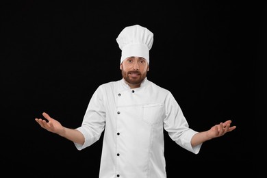 Photo of Puzzled mature male chef on black background