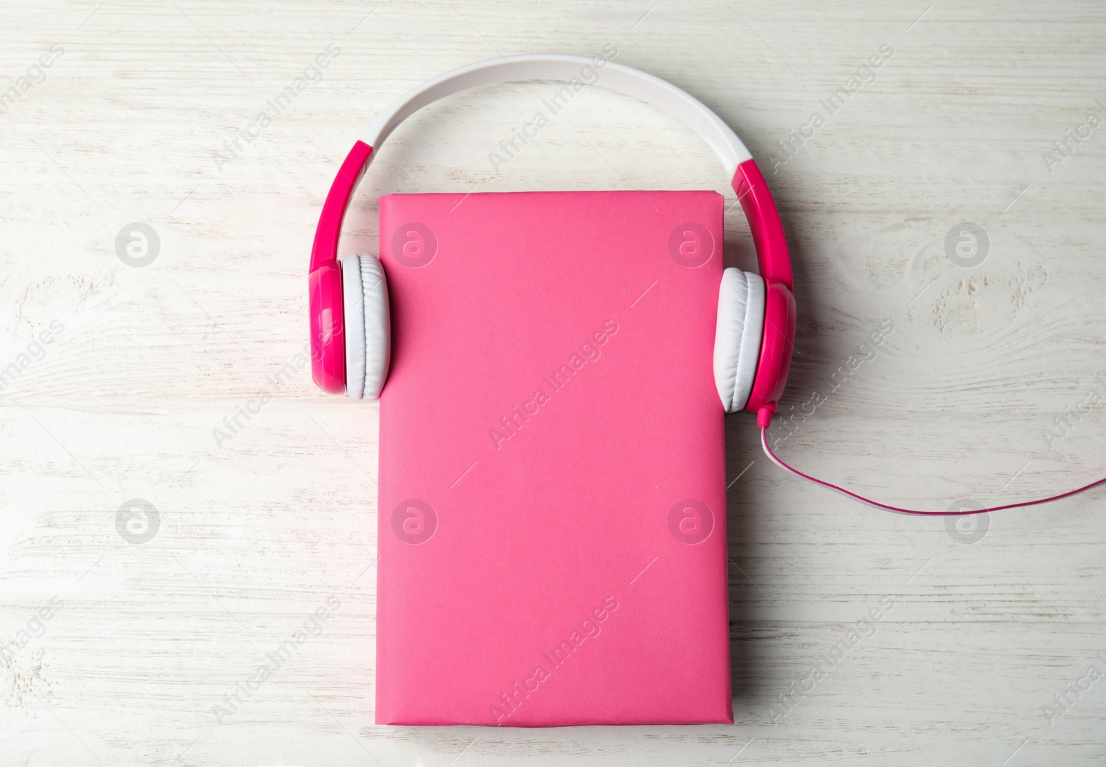 Photo of Book with blank cover and headphones on white wooden background, flat lay