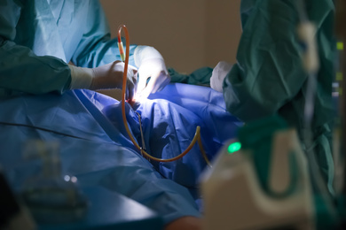 Photo of Professional doctors performing operation in surgery room, closeup