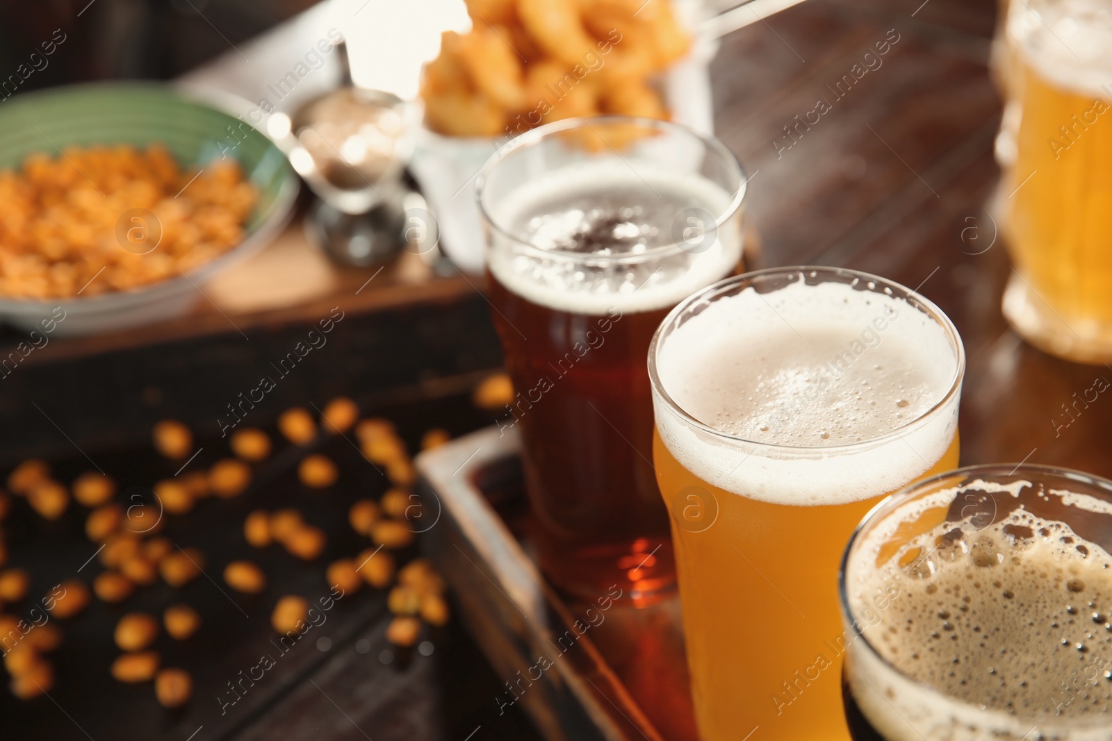 Photo of Glasses of tasty beer on wooden table, closeup