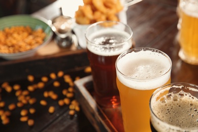 Photo of Glasses of tasty beer on wooden table, closeup