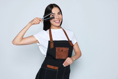 Photo of Portrait of happy hairdresser with professional combs on light background