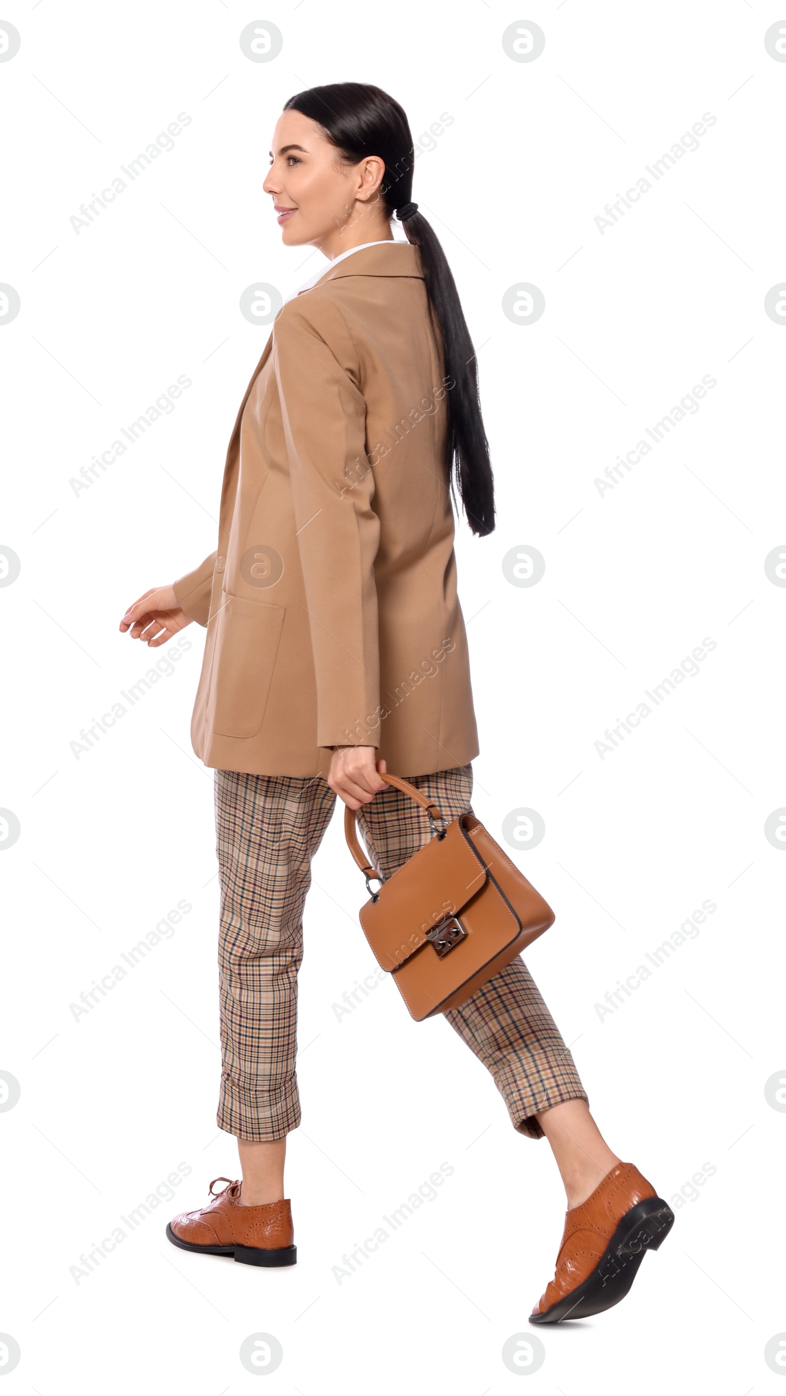 Photo of Young businesswoman with stylish bag walking on white background