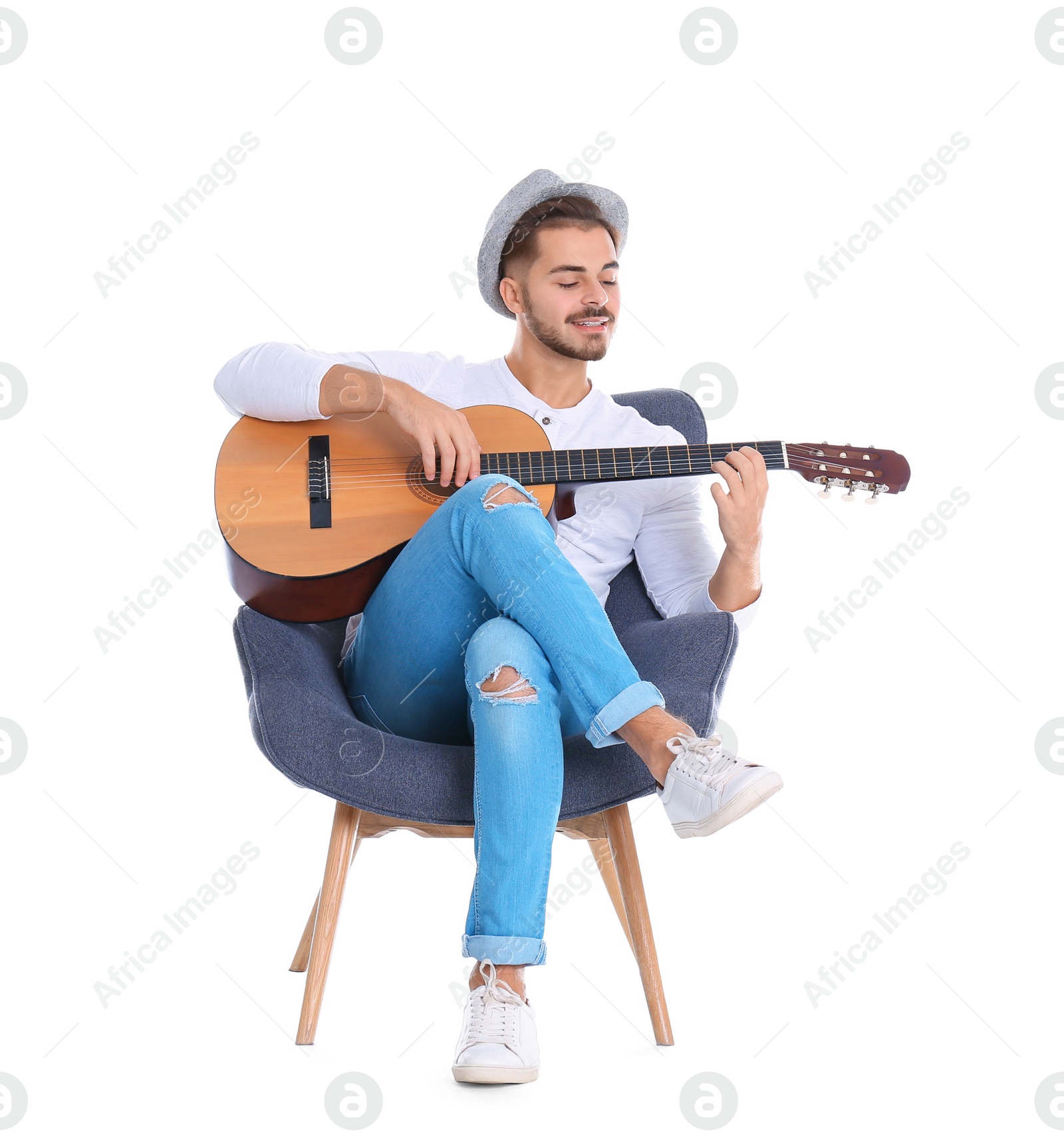 Photo of Handsome young man with guitar in armchair on white background