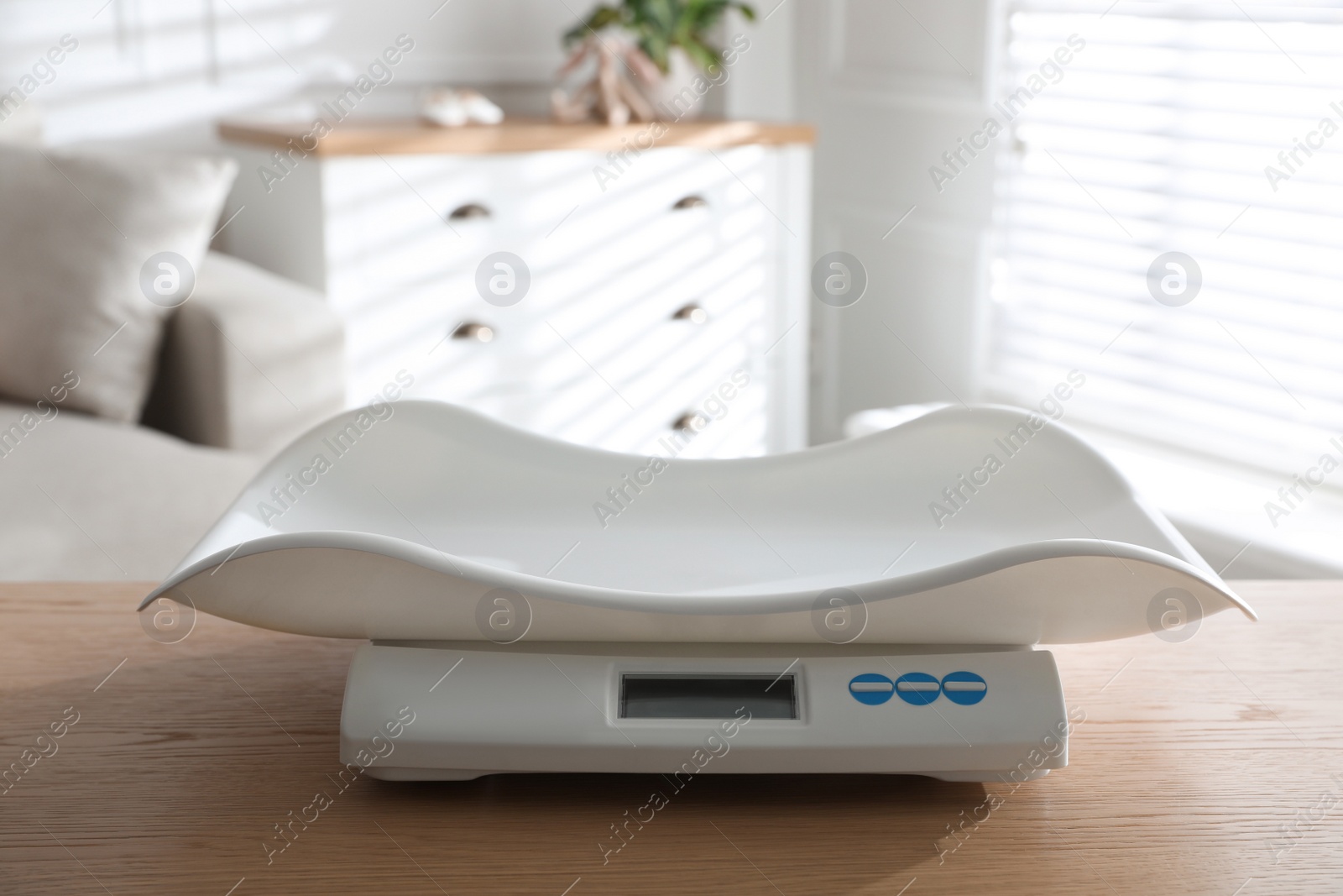 Photo of Modern digital baby scales on wooden table in room