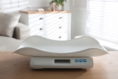 Modern digital baby scales on wooden table in room