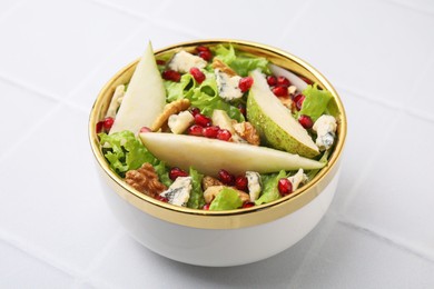 Photo of Delicious pear salad in bowl on light tiled table, closeup