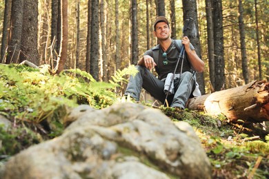 Photo of Hiker with trekking poles resting in mountain forest