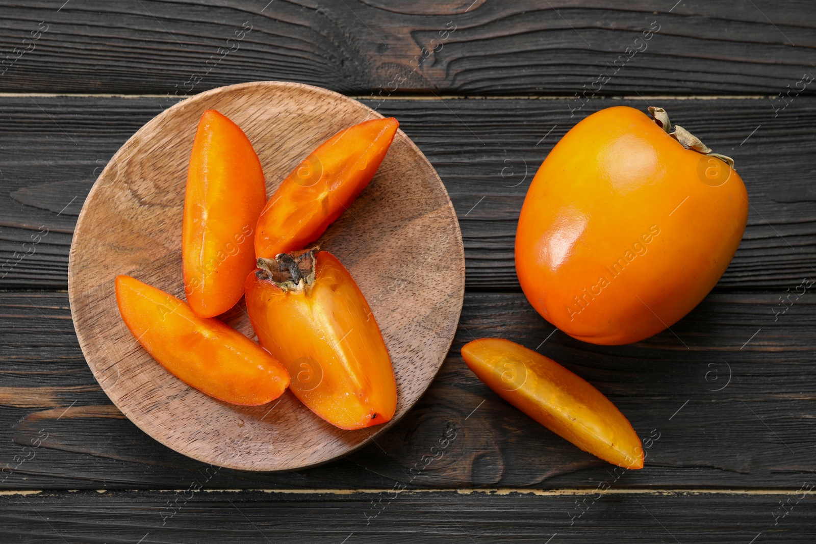 Photo of Delicious ripe persimmons on wooden table, top view