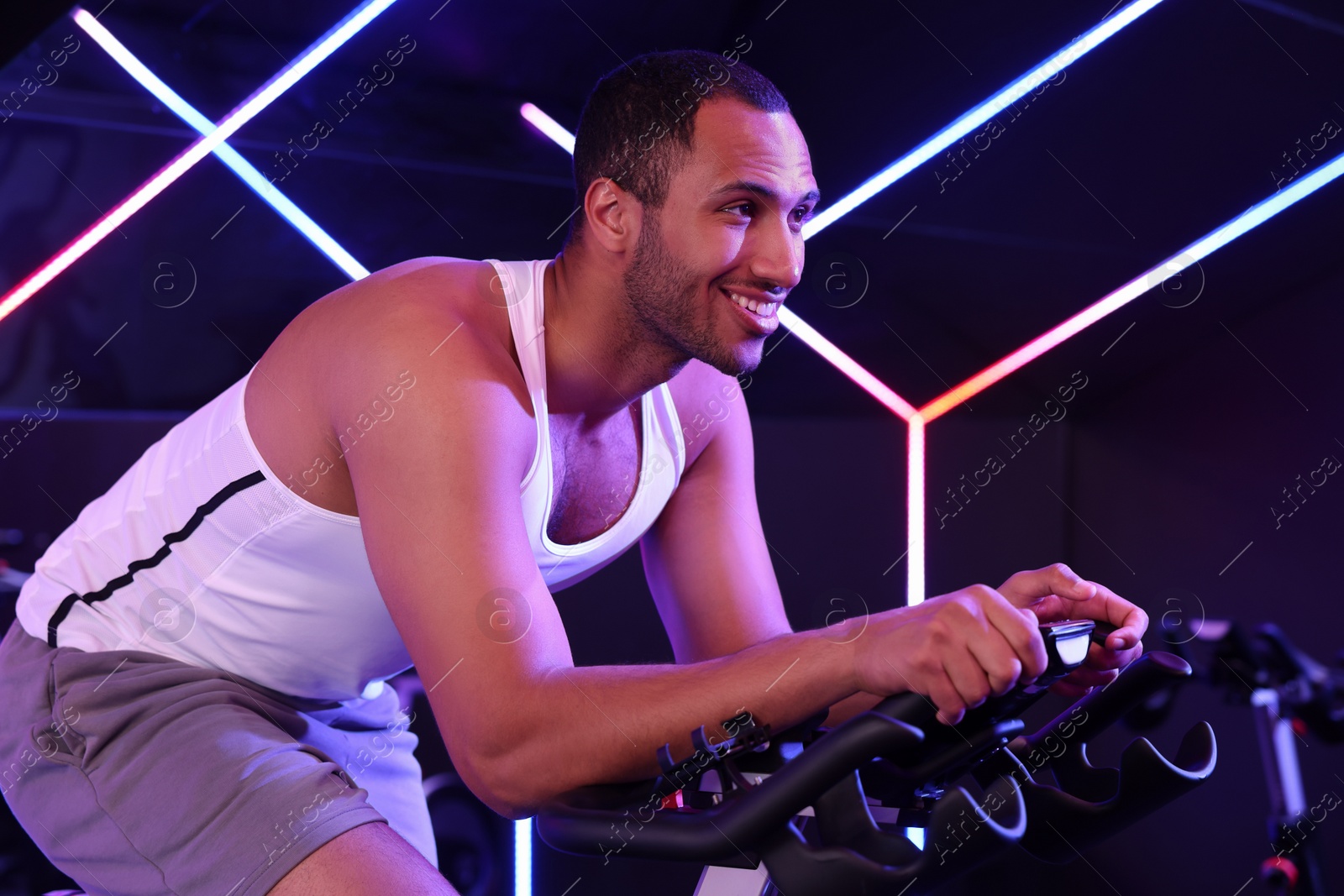 Photo of Young man training on exercise bike in fitness club