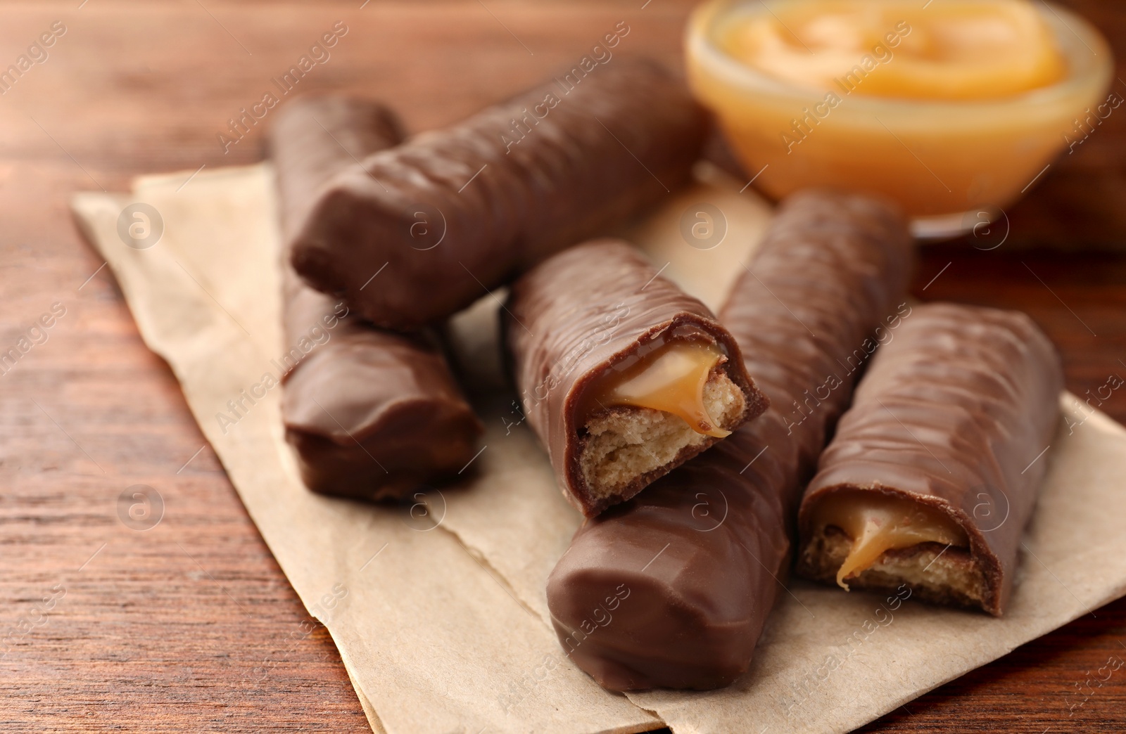 Photo of Sweet tasty chocolate bars with caramel on wooden table, closeup