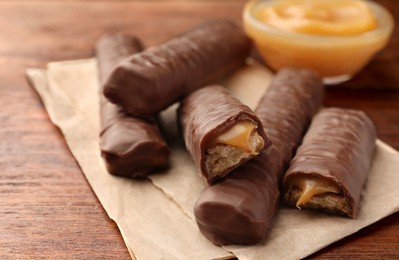Sweet tasty chocolate bars with caramel on wooden table, closeup