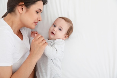 Photo of Portrait of mother with her cute baby lying on bed, top view. Space for text