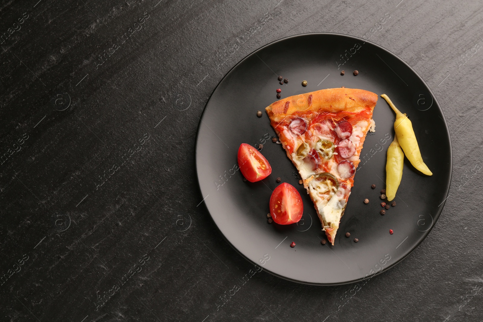 Photo of Plate with delicious pizza Diablo, pepper, tomato and peppercorns on dark textured table, top view. Space for text