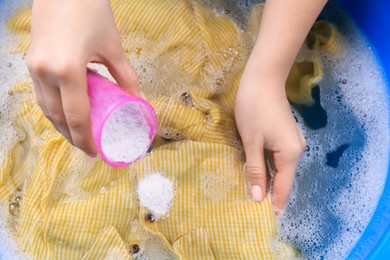 Photo of Woman pouring powder onto garment in basin, closeup. Hand washing laundry