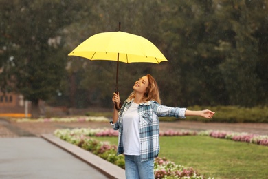 Photo of Happy young woman with umbrella under rain in park