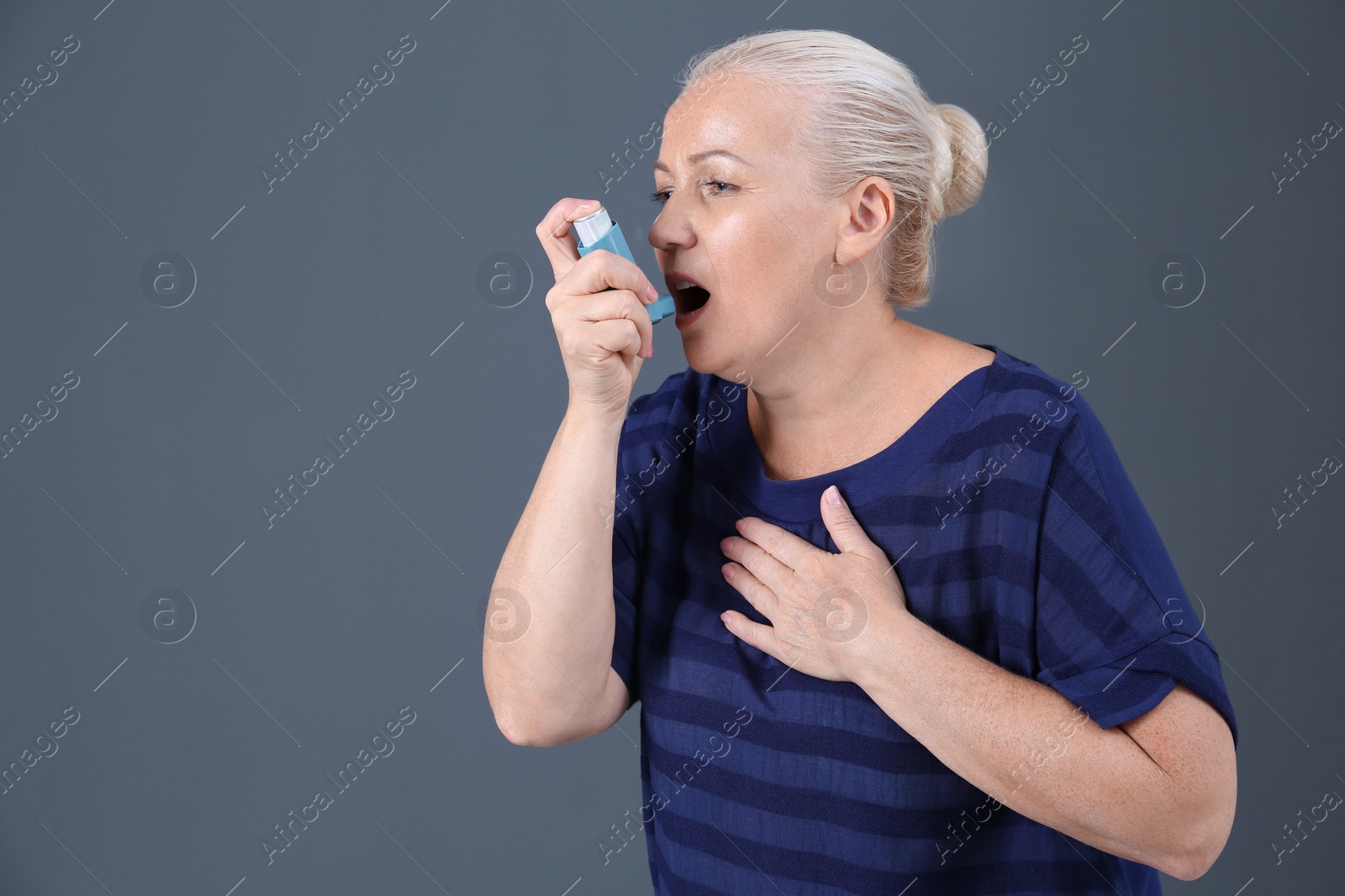 Photo of Woman using asthma inhaler on color background with space for text