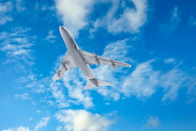 Airplane flying in blue sky with clouds. Air transportation