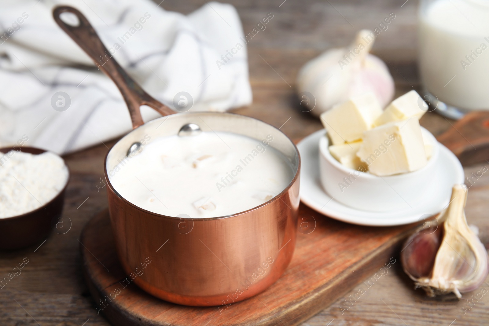 Photo of Delicious creamy sauce in pan on wooden table