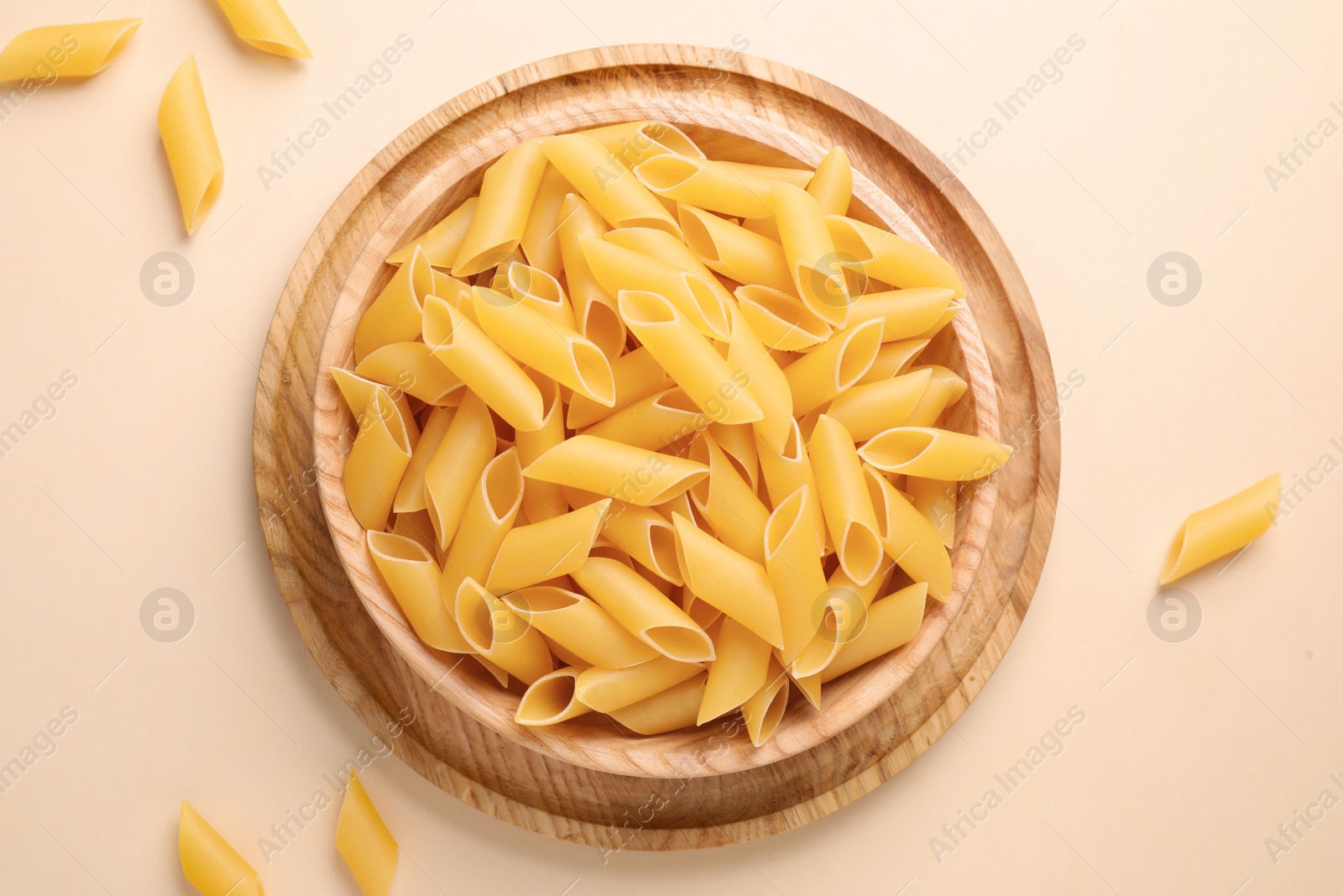 Photo of Pennoni pasta on beige background, flat lay