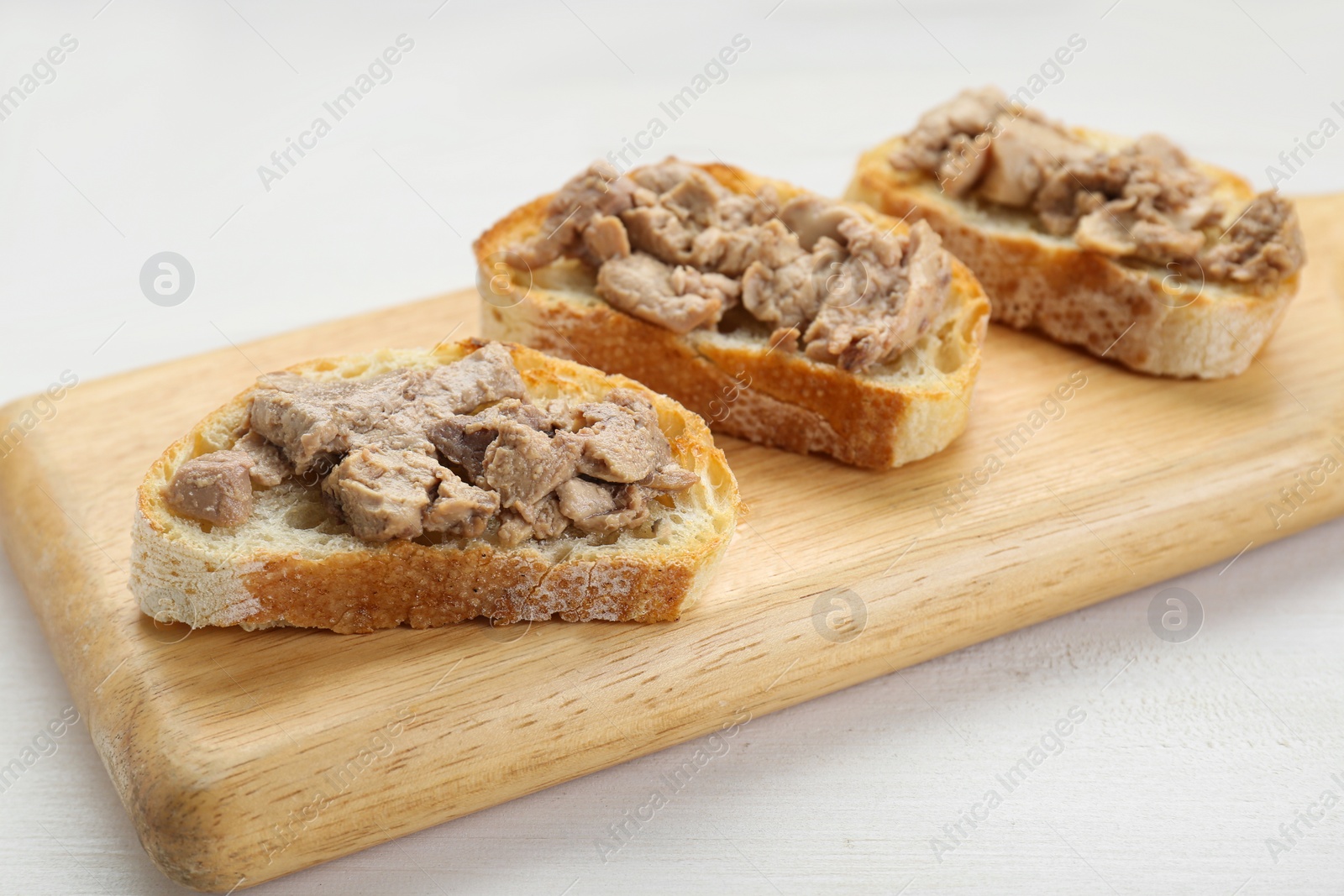 Photo of Tasty sandwiches with cod liver on white wooden table