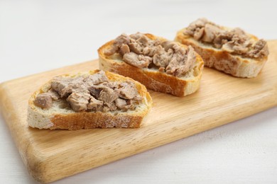 Photo of Tasty sandwiches with cod liver on white wooden table