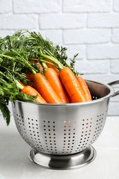 Colander with fresh ripe carrots on marble table