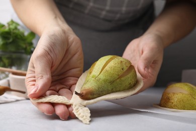 Photo of Woman making pastry with dough and fresh pears at white table, closeup