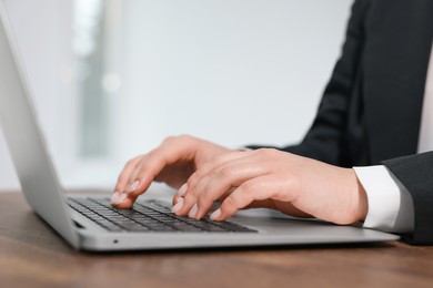 Woman working on laptop at wooden table closeup. Electronic document management