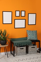 Photo of Empty frames hanging on orange wall in stylish room. Mockup for design