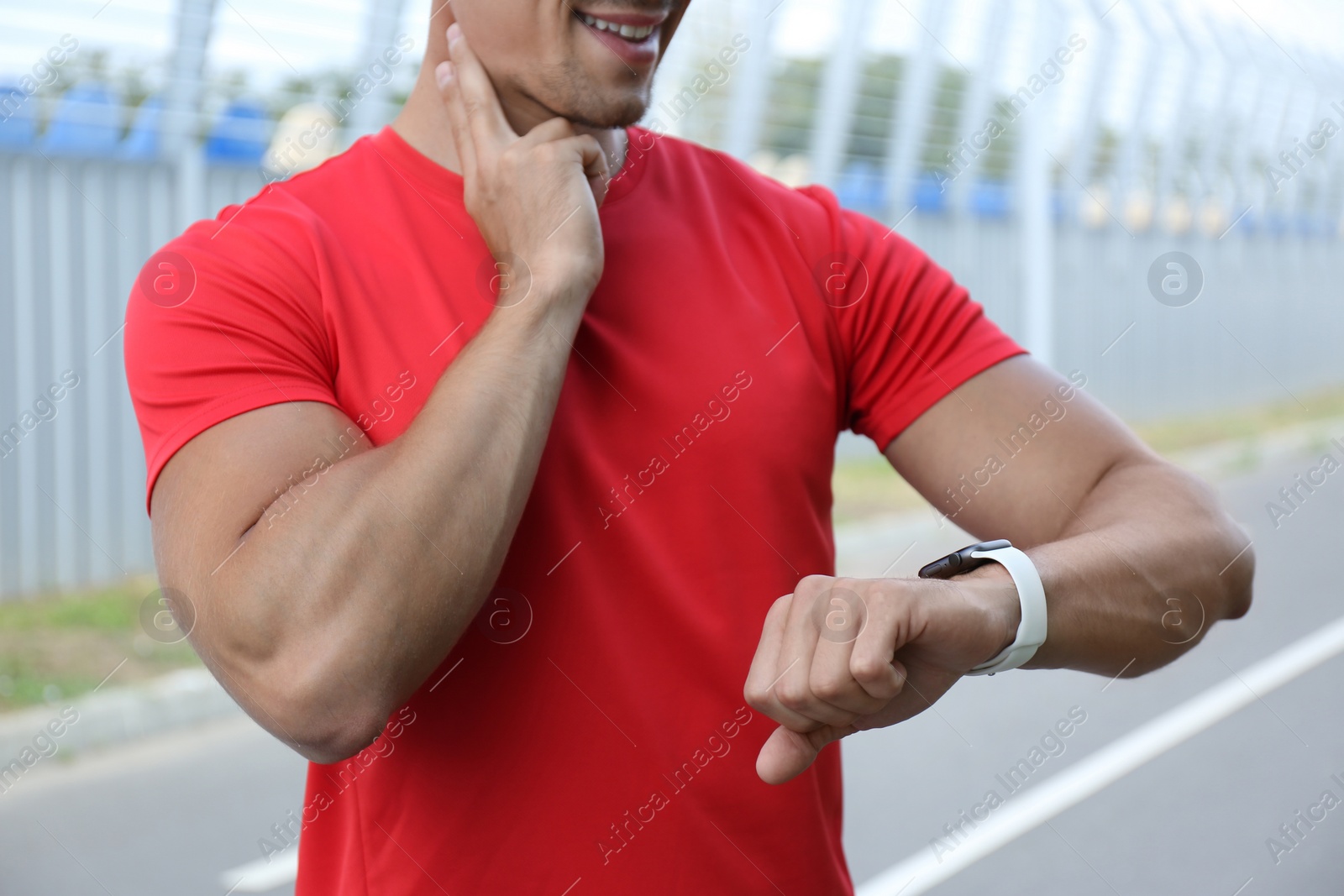 Photo of Young man checking pulse after training outdoors, closeup