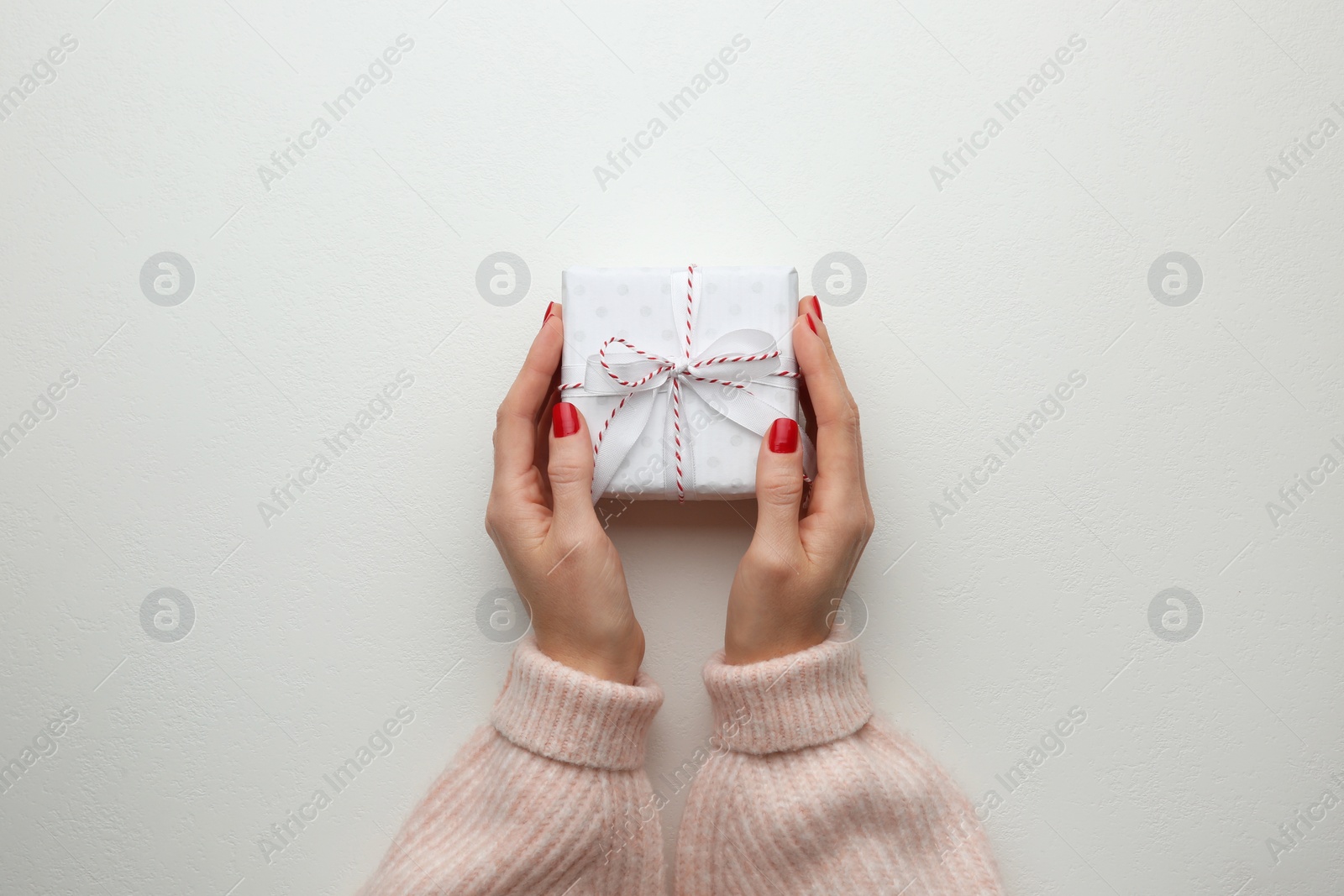 Photo of Woman holding Christmas gift box on white background, top view