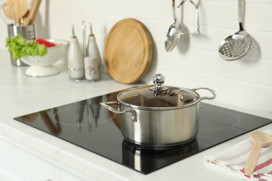 Photo of Shiny pot on electric stove in kitchen. Cooking utensil