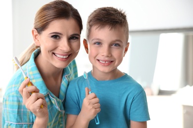 Photo of Portrait of mother and her son with toothbrushes in bathroom. Personal hygiene