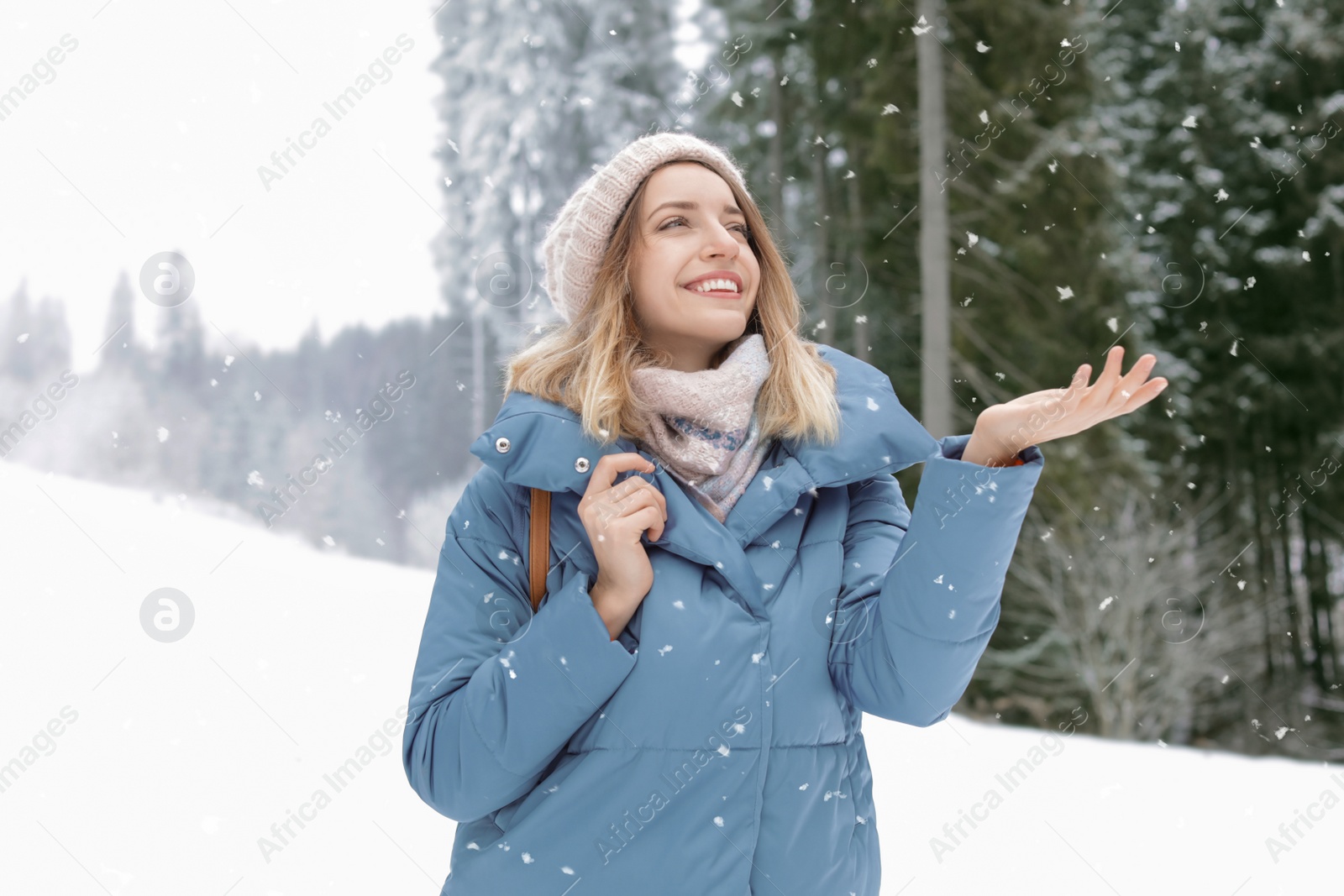 Photo of Happy young woman in warm clothes outdoors. Winter vacation