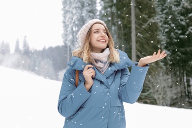 Photo of Happy young woman in warm clothes outdoors. Winter vacation