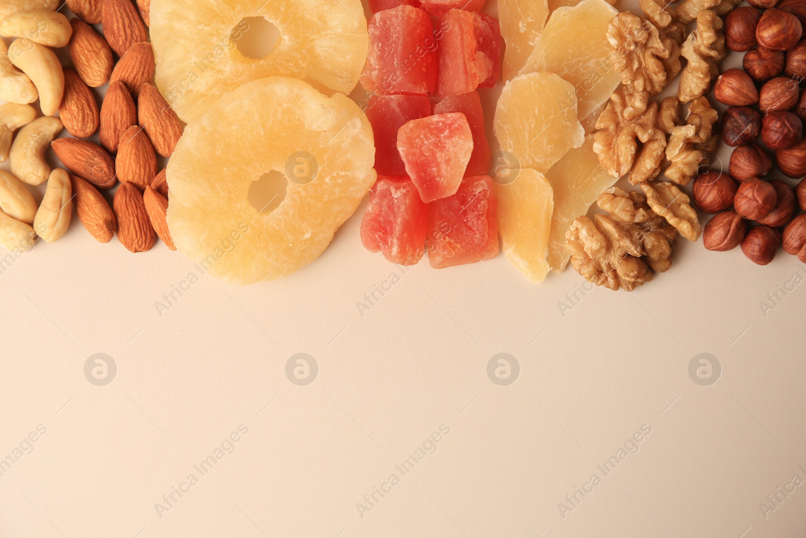 Photo of Different tasty nuts and dried fruits on beige background, flat lay. Space for text