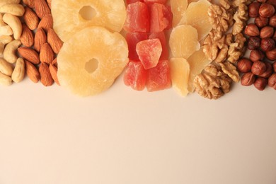 Different tasty nuts and dried fruits on beige background, flat lay. Space for text