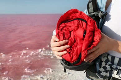 Woman with sleeping bag on coast of pink lake